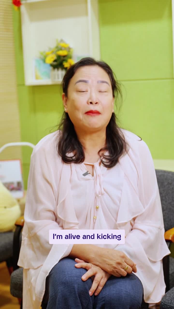 A cancer survivor seated and speaking to camera, captioned: I'm alive and kicking.